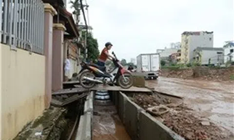 Đường cao hơn nền nhà gần 1 m, người dân chật vật 'bắc cầu' để đi lại